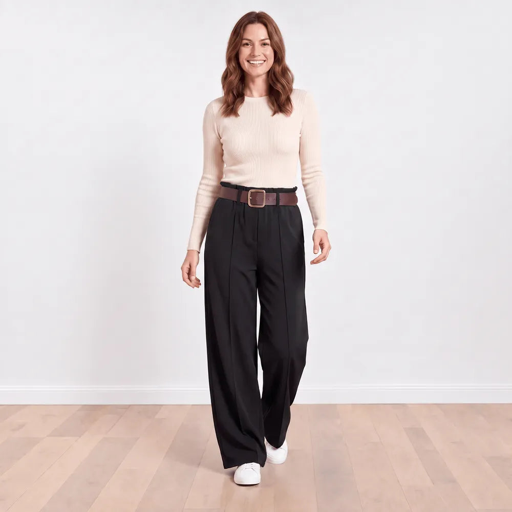 Ellana wide-leg pleated trousers in black styled with a cream ribbed knit top and white trainers, relaxed front walking view
