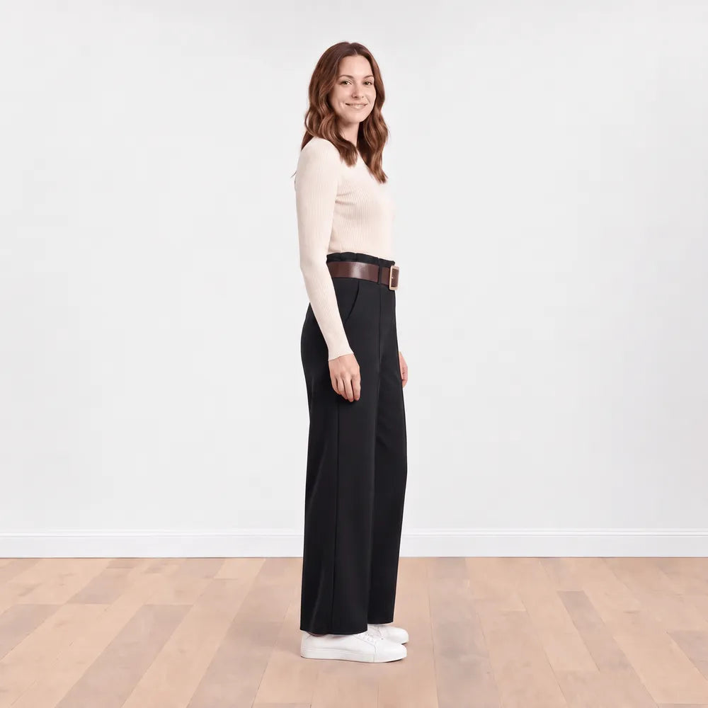 Side profile of Ellana wide-leg pleated trousers in black showing the high waistband, frill detail and full leg drape