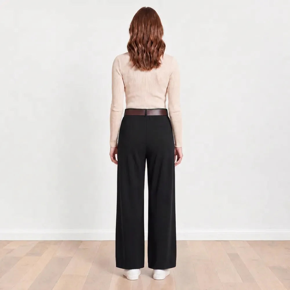 Back view of Ellana wide-leg pleated trousers in black with brown leather belt and white trainers