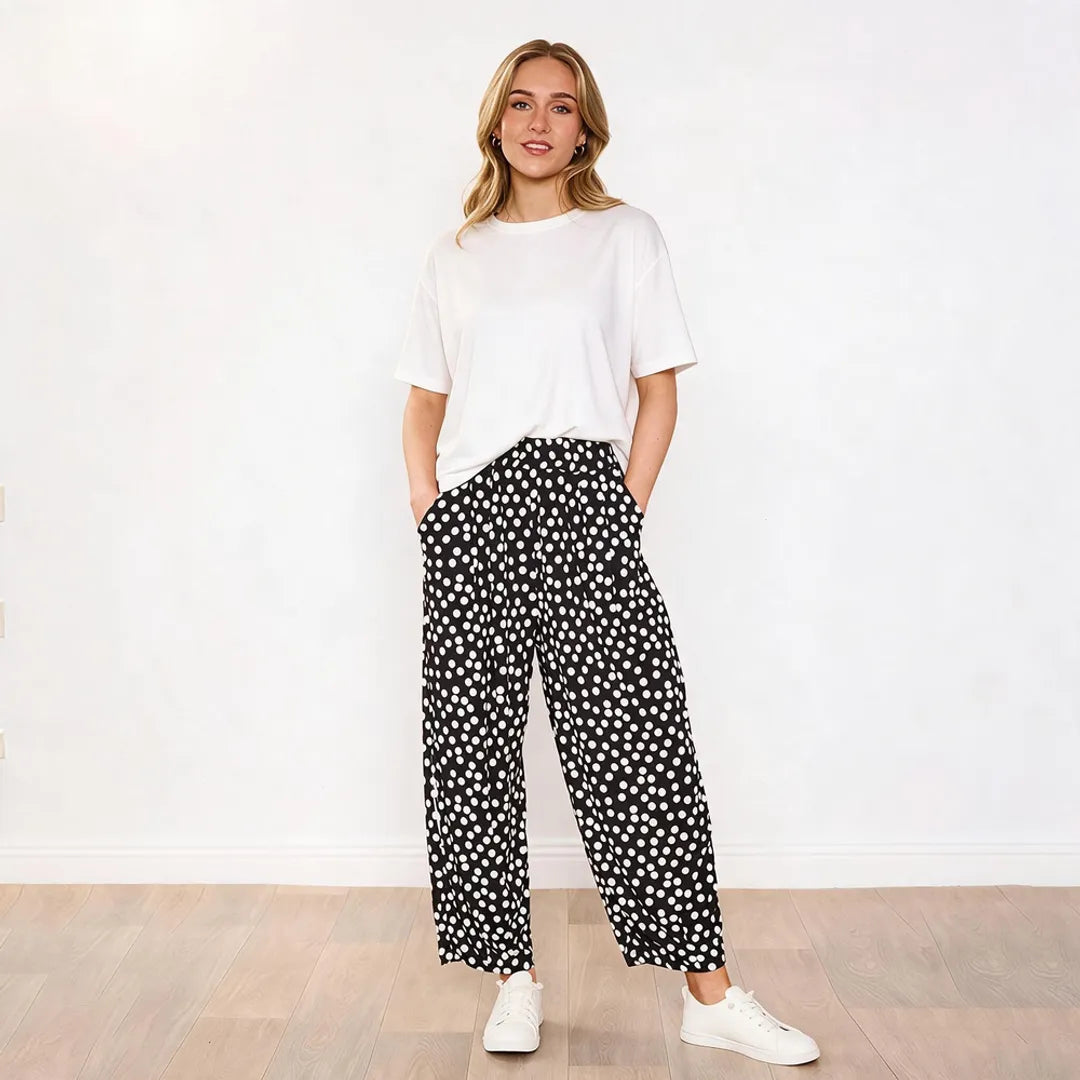 Model wearing white boxy tee with Fraya black polka dot wide-leg trousers, front view hands in pockets