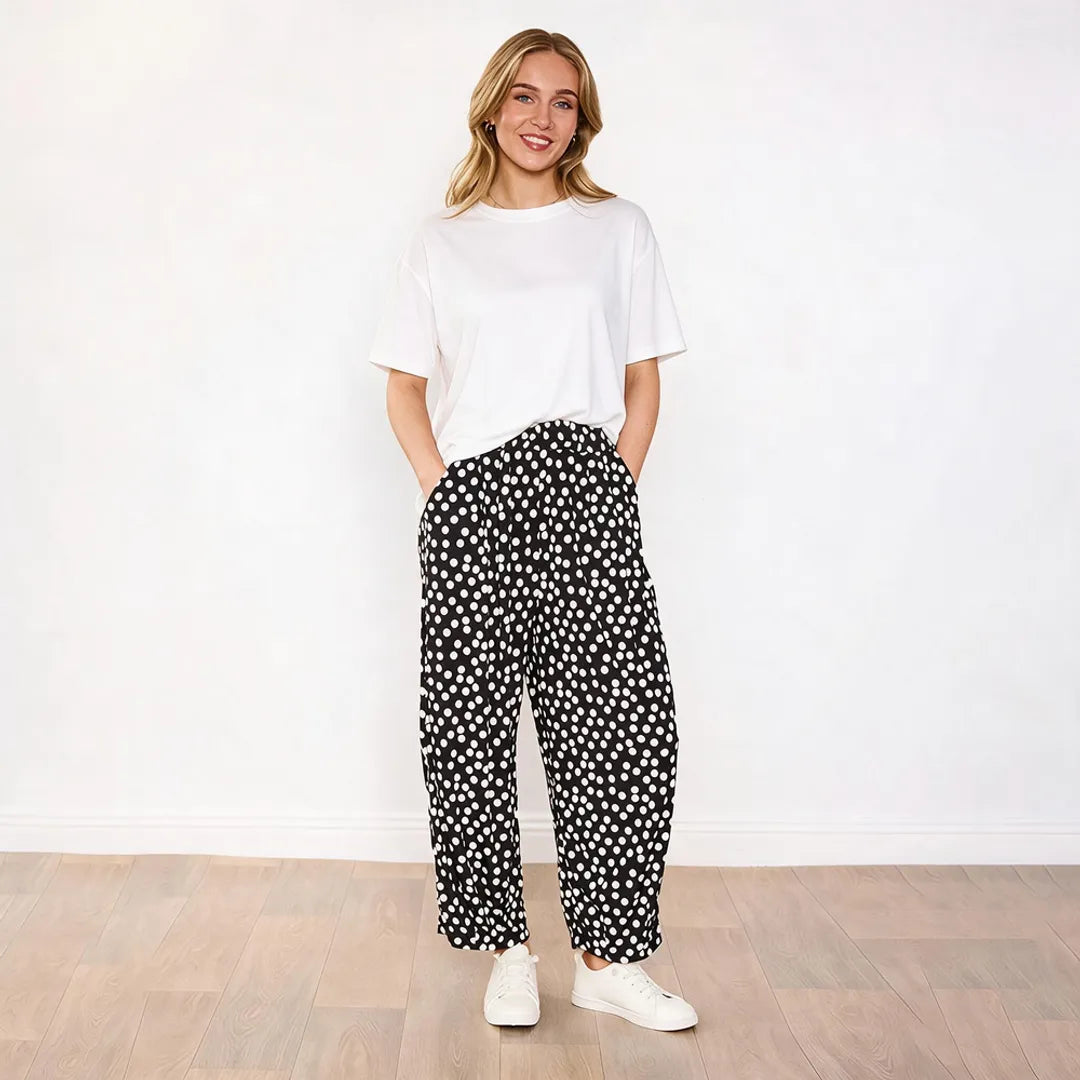 Model wearing white boxy tee with Fraya black polka dot wide-leg trousers, relaxed front view