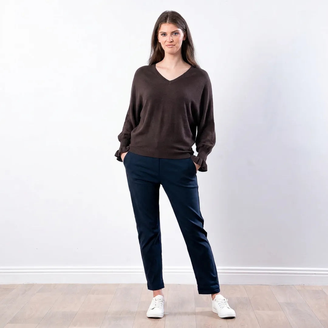 Woman wearing chocolate brown Lexie batwing V-neck knit top with navy trousers, front view