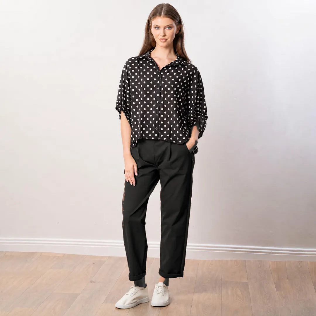 Athena Top in black polka dot, front view worn with black tapered trousers and white trainers