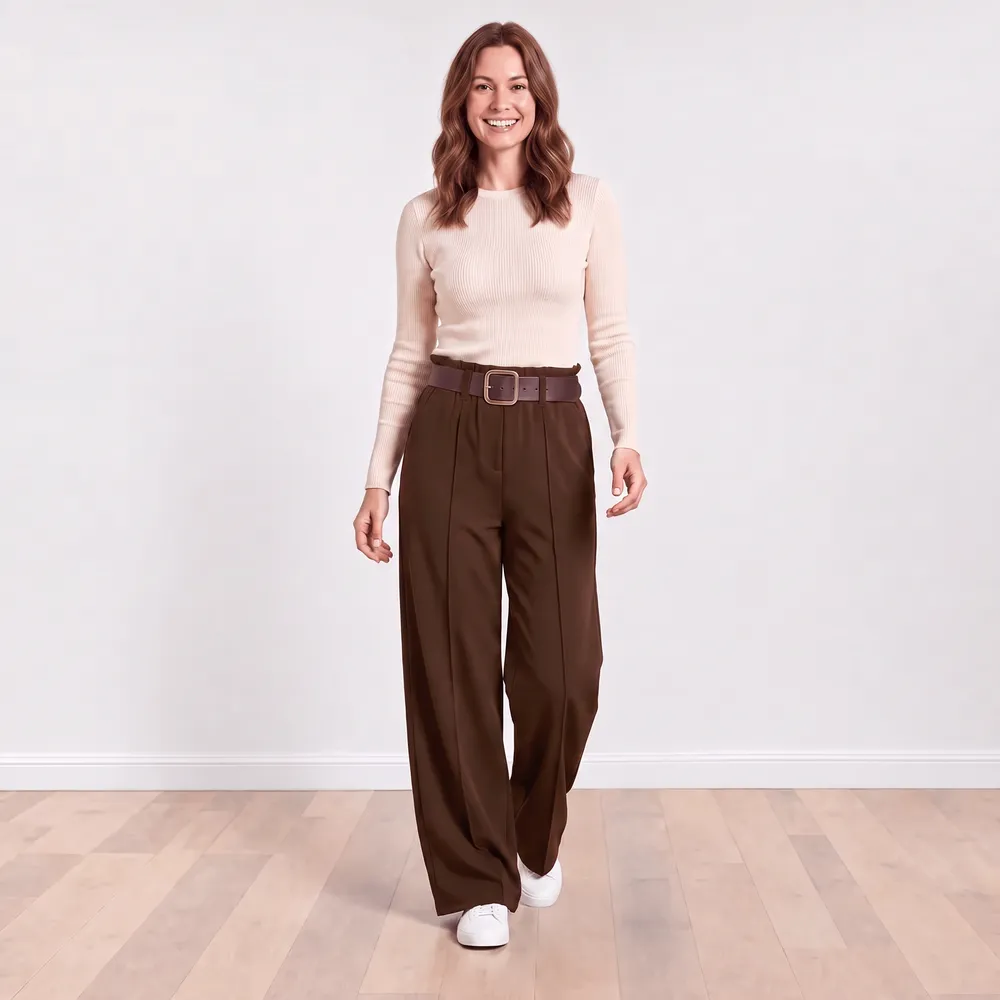 Ellana Trousers in brown — model wearing high-waisted wide-leg paperbag trousers with brown leather belt and white trainers, front view