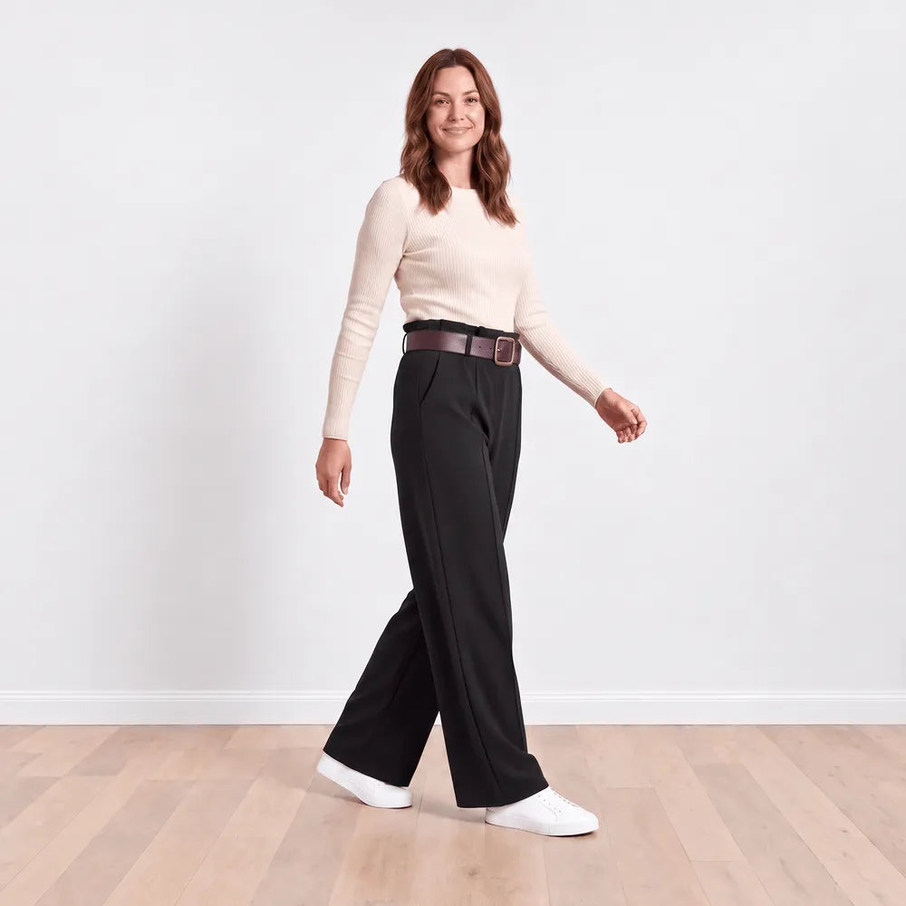 Ellana wide-leg pleated trousers in black shown in motion, three-quarter walking view with cream knit top and brown belt