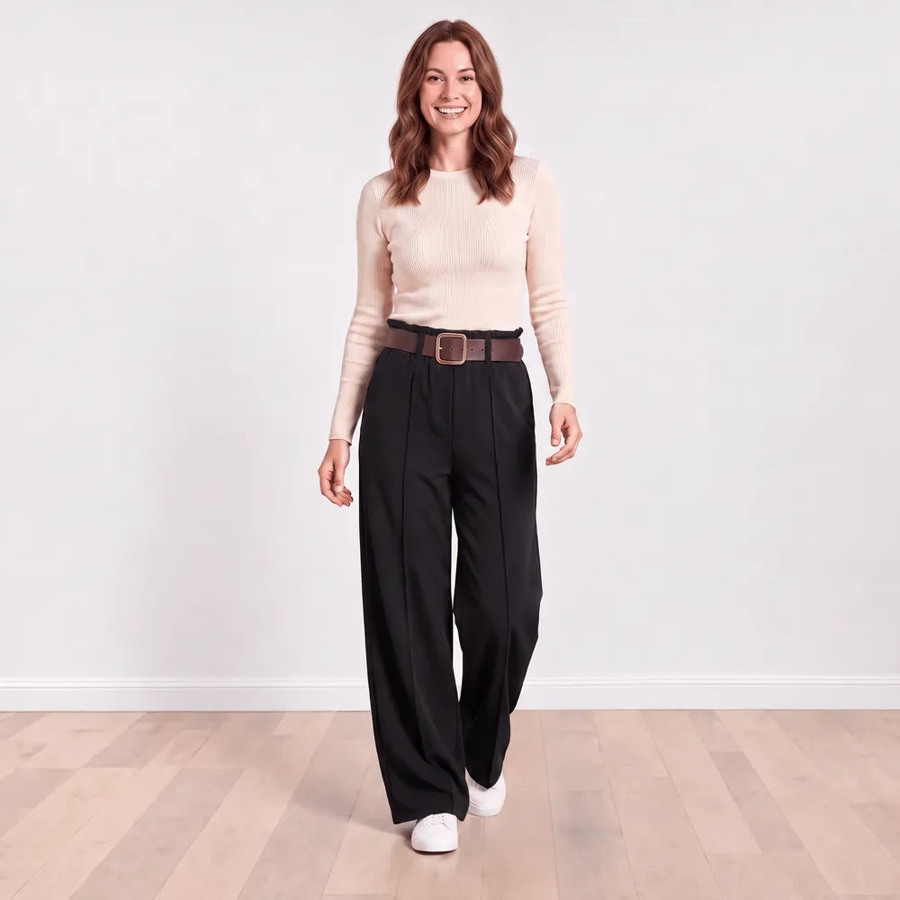Smiling model in Ellana wide-leg pleated trousers in black with cream ribbed knit top, cheerful front view
