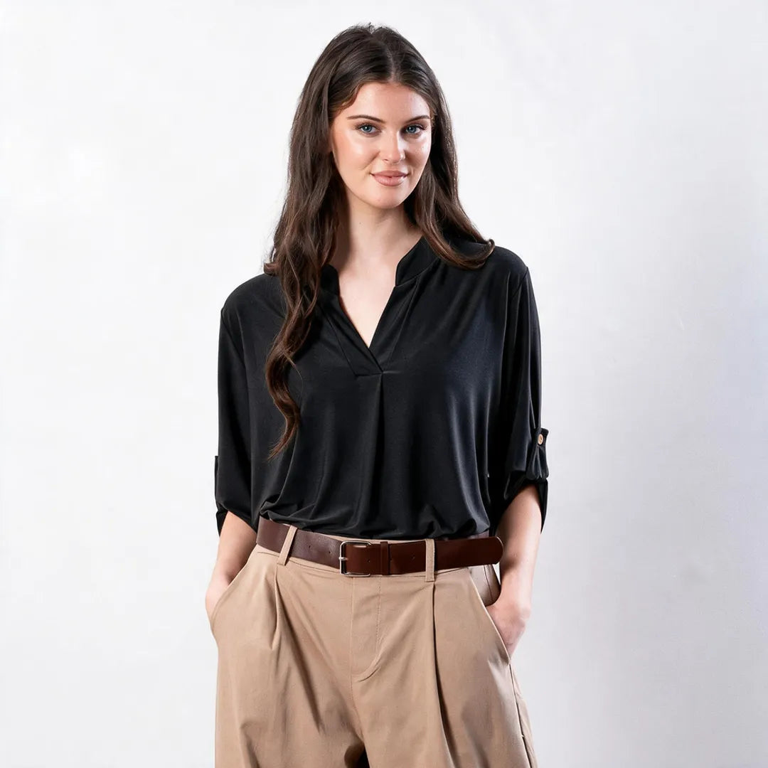 Sharlene Top in black — close-up front view of notch V-neck jersey top with centre pleat, worn with tan wide-leg trousers and brown leather belt
