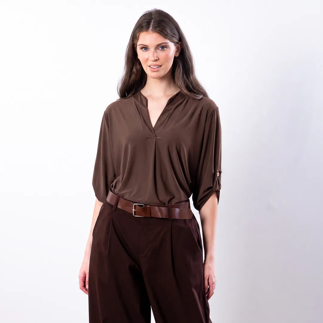Sharlene Top in brown — waist-up front view showing relaxed jersey drape, dropped shoulders and 3/4 roll-tab sleeves, styled with brown leather belt